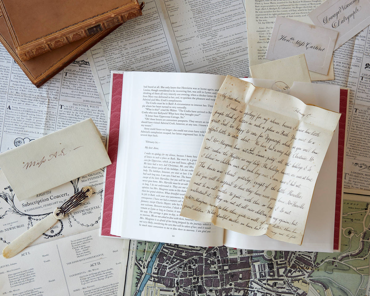 Open book with handwritten pages on a surface with old documents and a feather pen.
