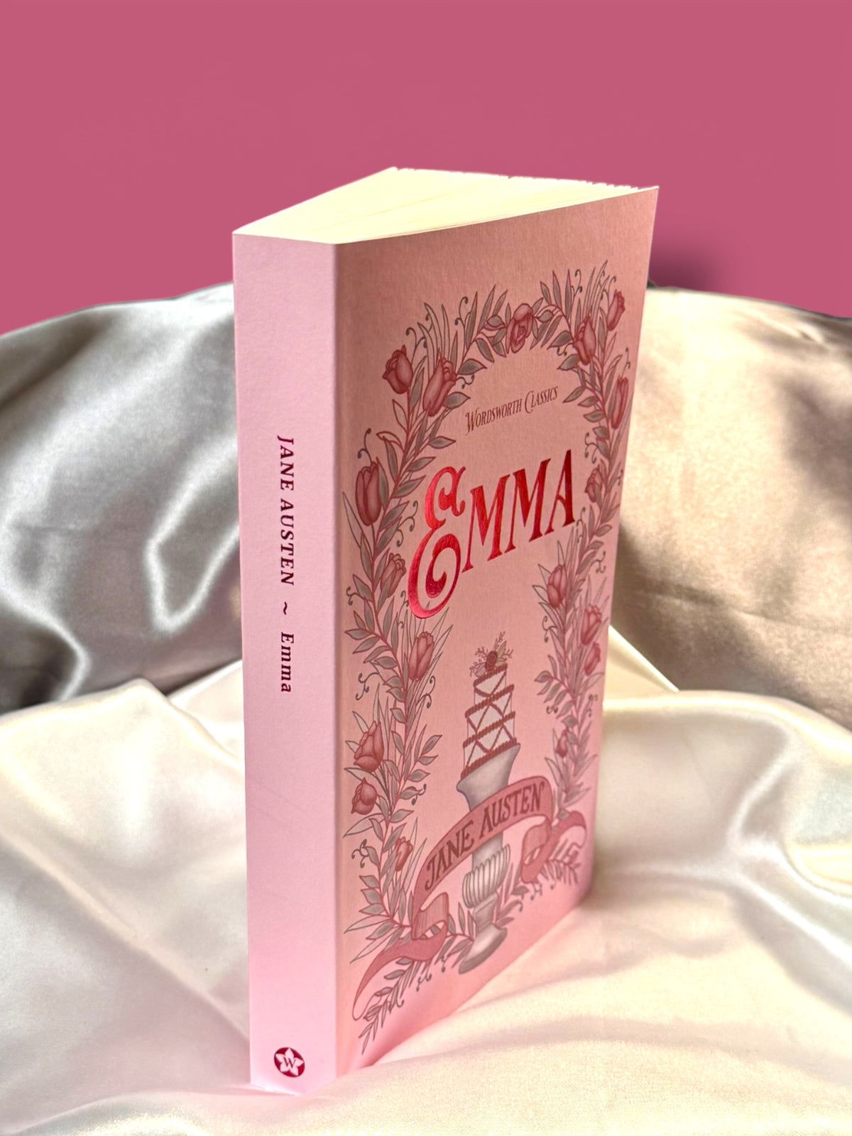 Emma by Jane Austen Wordsworth Classics paperback standing at an angle, displaying its pink illustrated front cover and spine.