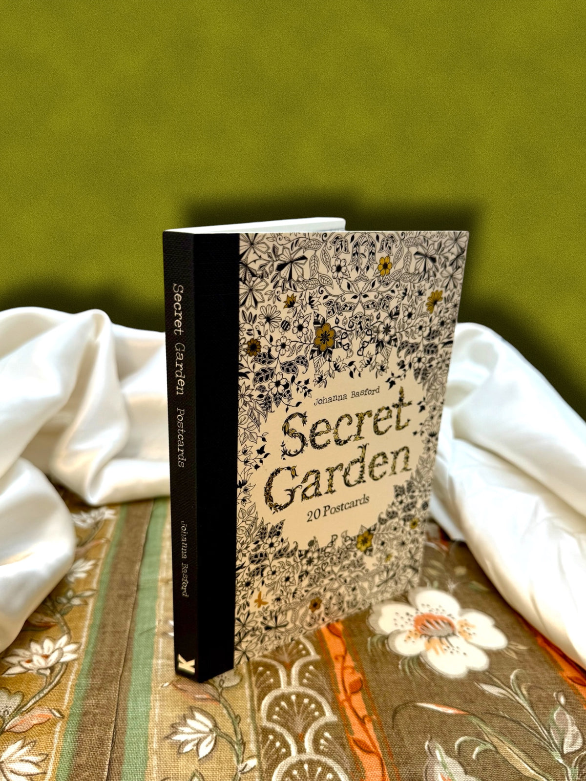Side view of Secret Garden 20 detachable coloring postcards by Johanna Basford, showing the thickness of the postcard collection.