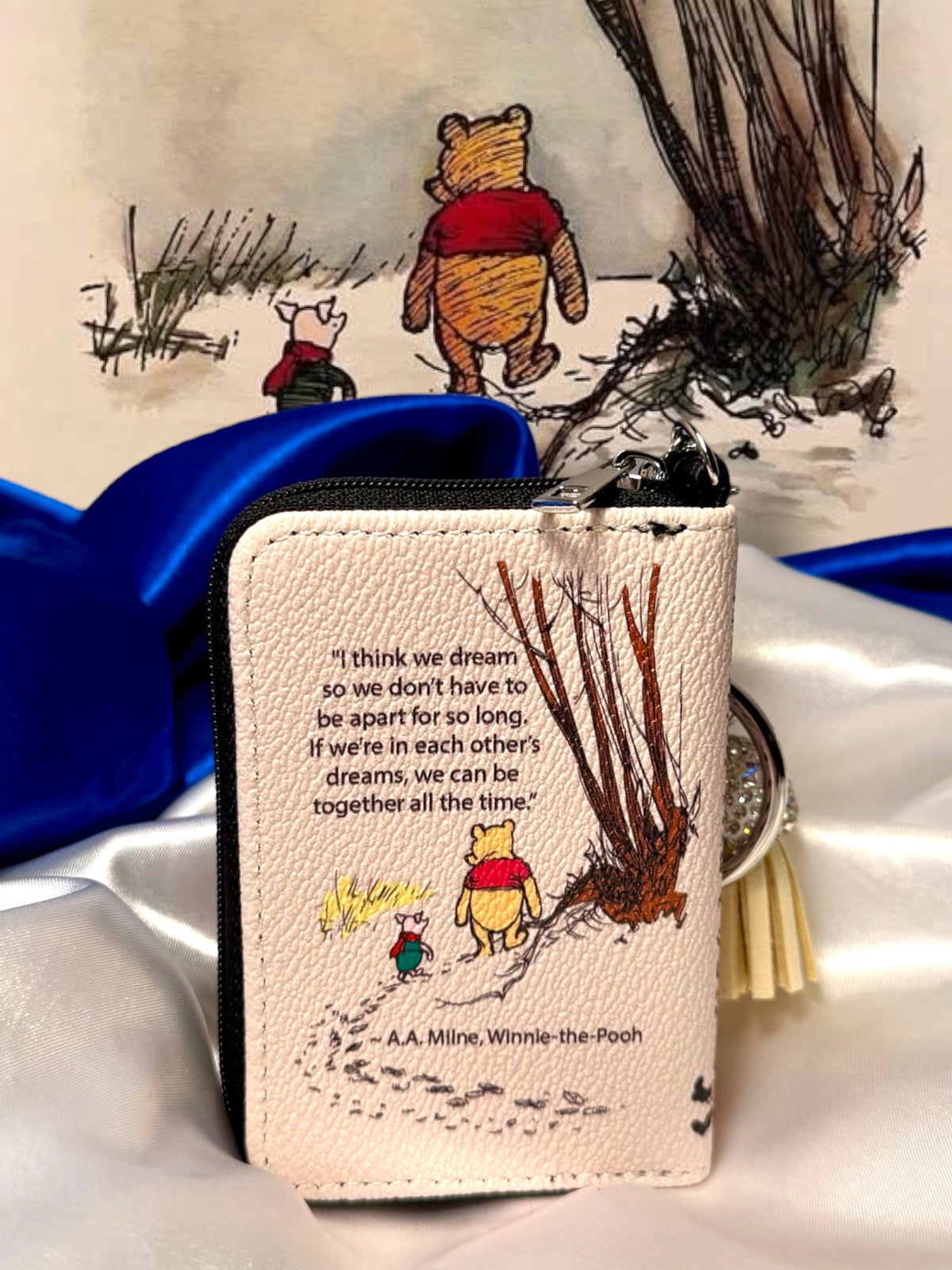 Back of Winnie-the-Pooh miniature coin purse featuring Pooh and Piglet walking beside a tree and a printed quotation on the ivory cover.