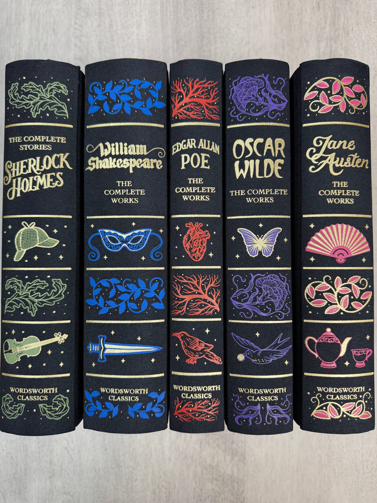Set of five classic literature books with decorative covers on a wooden surface.