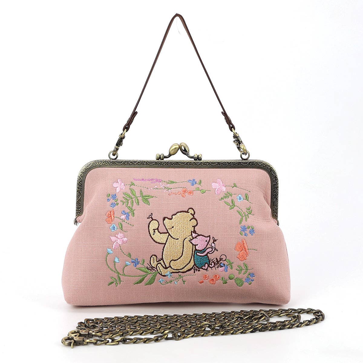 Pink Winnie-the-Pooh and Piglet embroidered kisslock handbag with floral design, antique-style metal clasp, wrist strap, and chain shoulder strap.