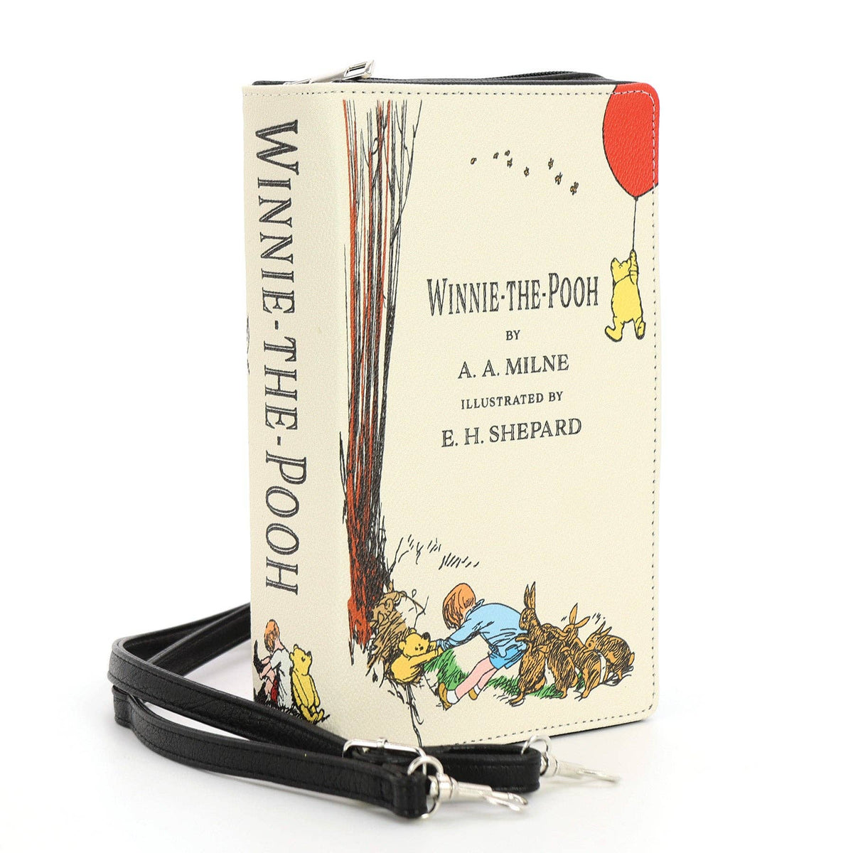 The House at Pooh Corner beige book clutch bag shown at an angle with illustrated literary cover, zipper closure, and detachable strap hardware.