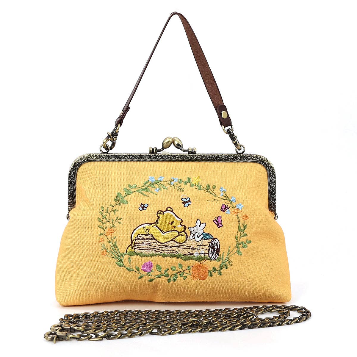 Winnie-the-Pooh and Piglet embroidered kisslock handbag featuring the two friends lounging on a log, linen blend fabric, and vintage-style metal clasp.