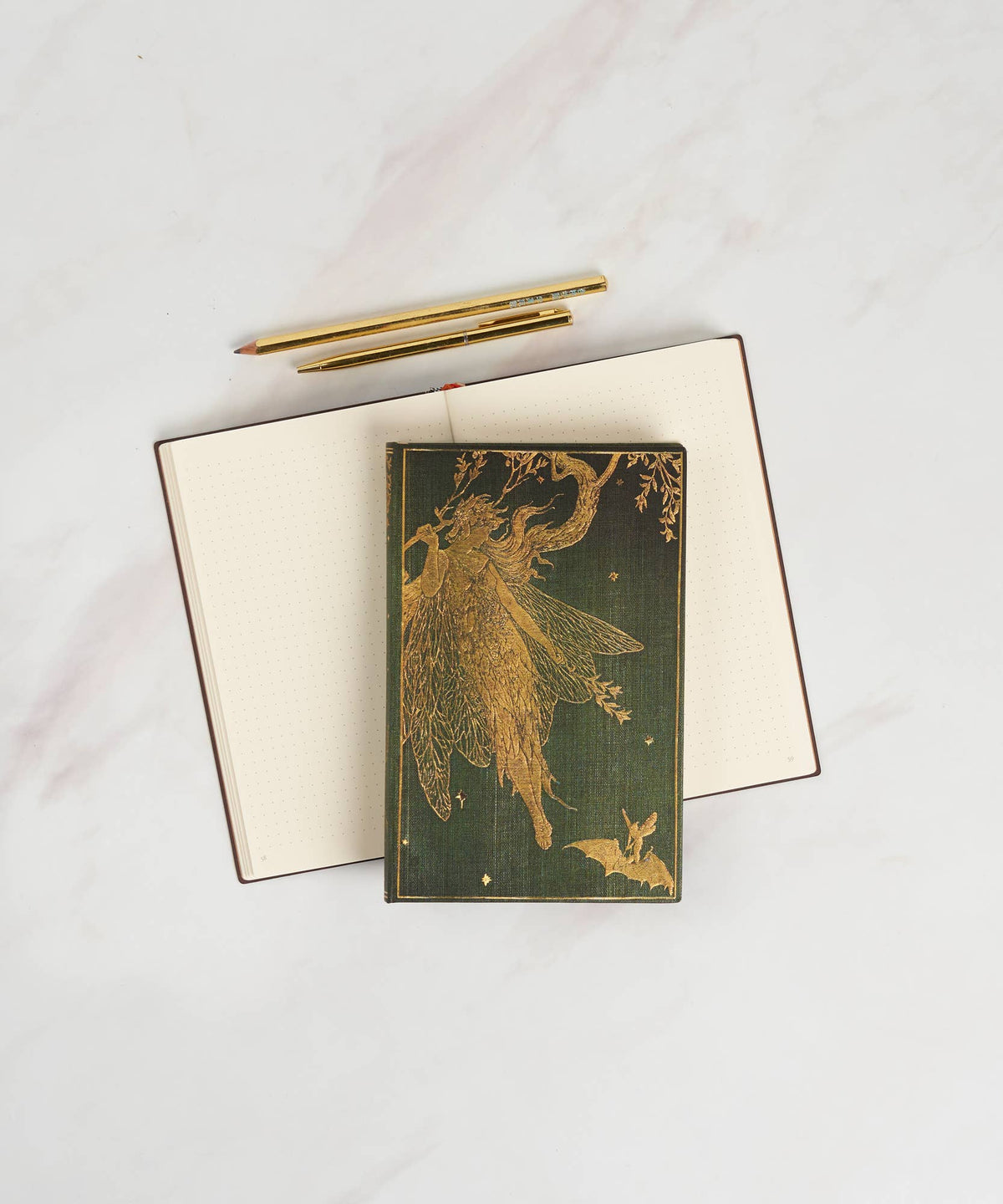 Notebook with gold fairy design on cover and gold pen on white background