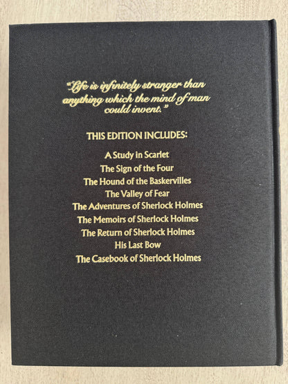 Black book cover with gold text listing Sherlock Holmes stories on a beige background