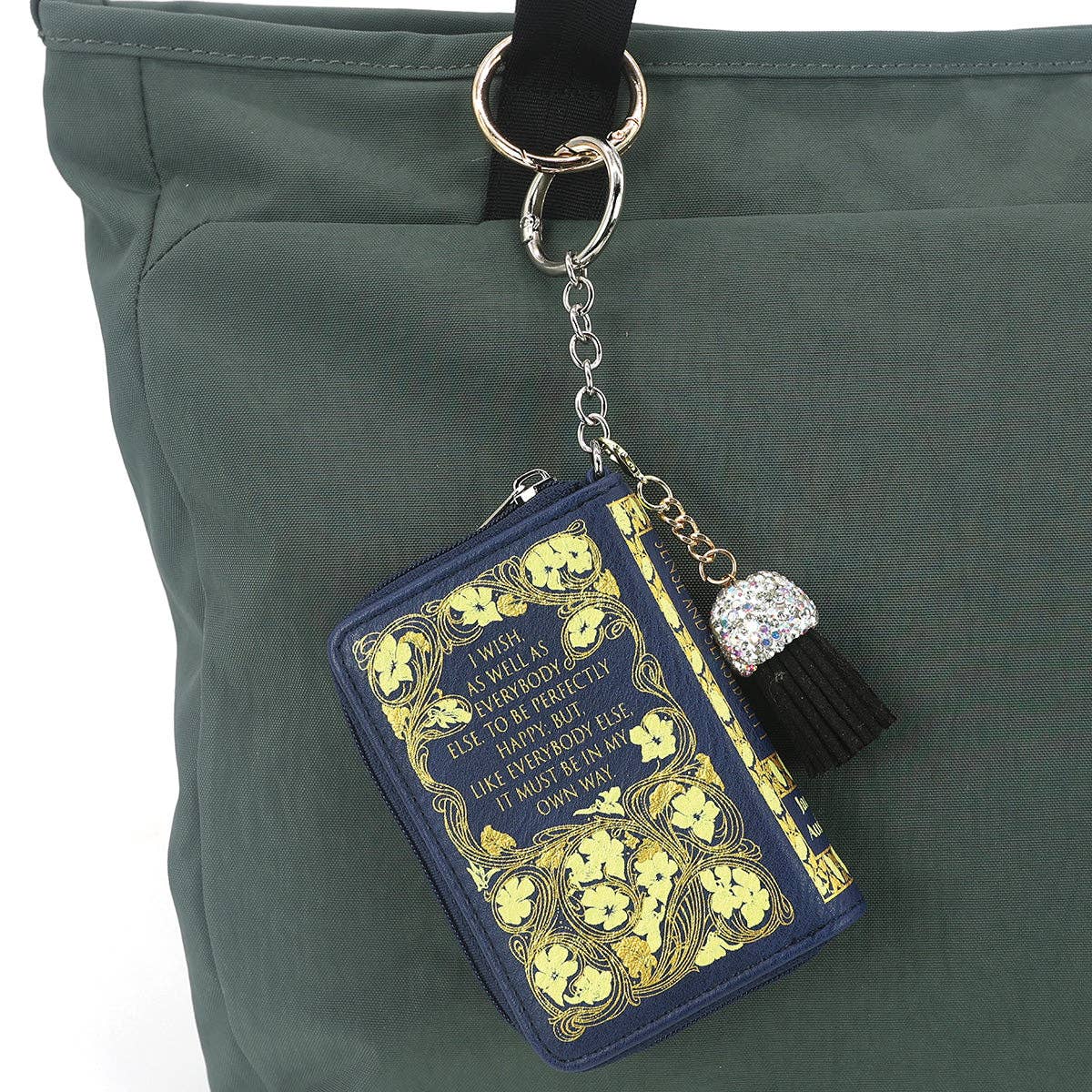 Decorative keychain with book design and tassel on a green bag