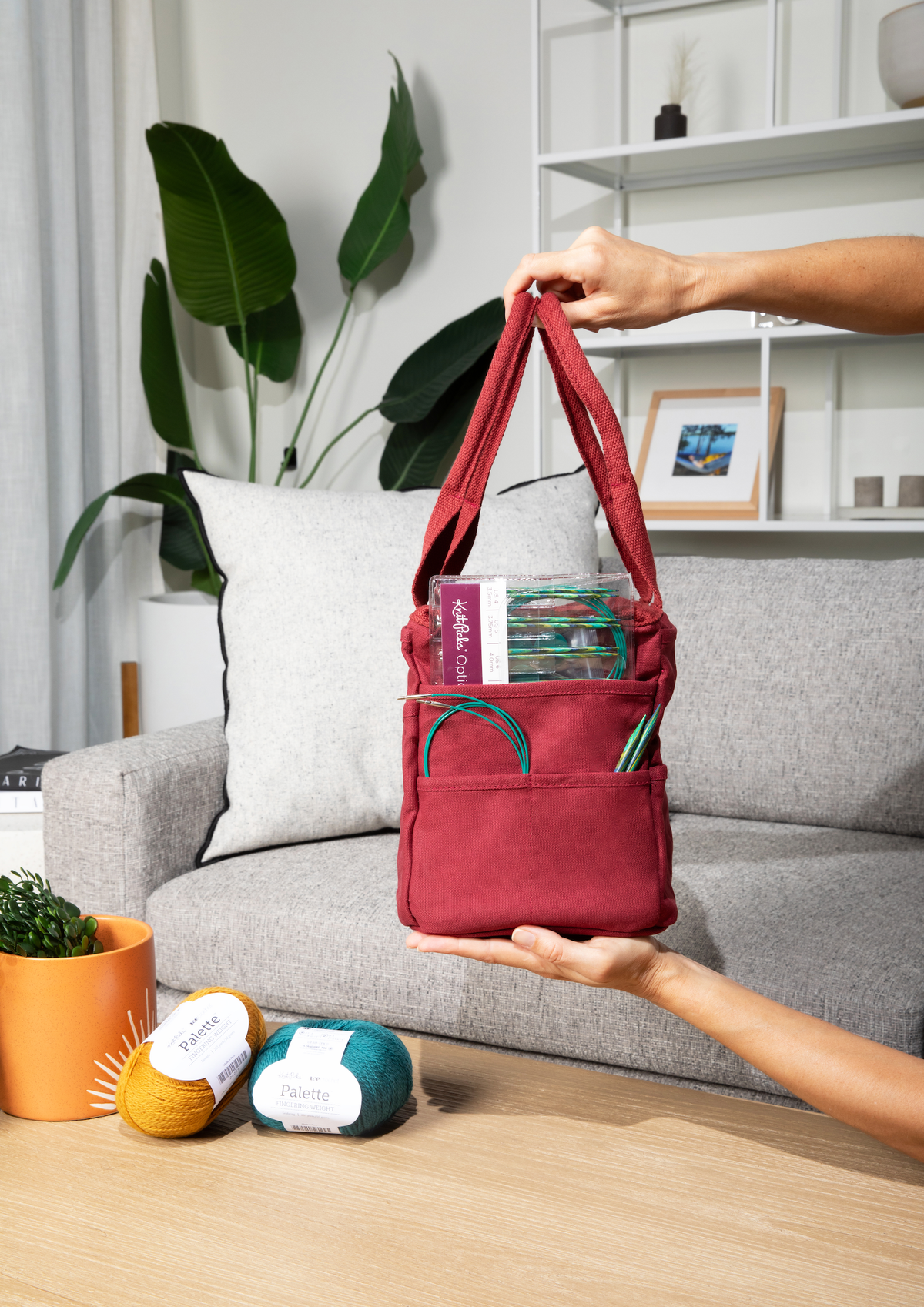 Sangria bag held by a person in a living room with a couch and plants.