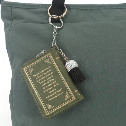 Green book-shaped keychain with tassel on a green bag