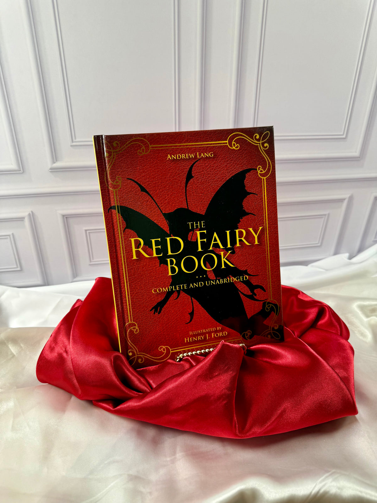 The Red Fairy Book by Andrew Lang, illustrated hardcover with decorative gold lettering, displayed on satin at StoryGiftStudio.