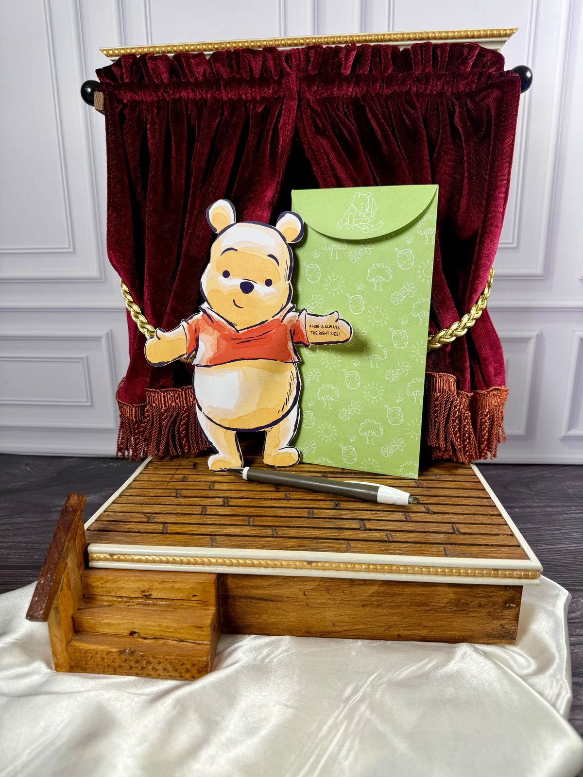 Winnie the Pooh Hugs folding notecards arranged upright in a miniature theater-style display with red curtains.