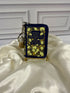 Sense and Sensibility miniature book coin purse and bag charm in navy blue with gold floral artwork, displayed on a gold stand against ivory satin.