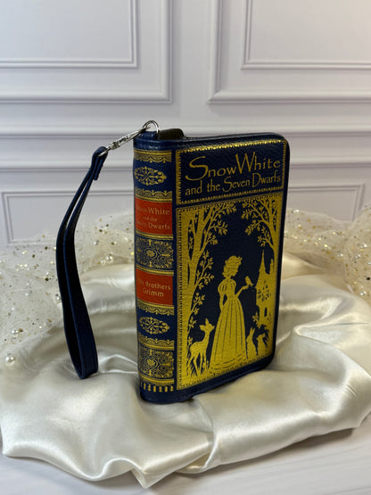 Snow White book wallet angled to show decorative book spine, gold artwork, and detachable wristlet strap.
