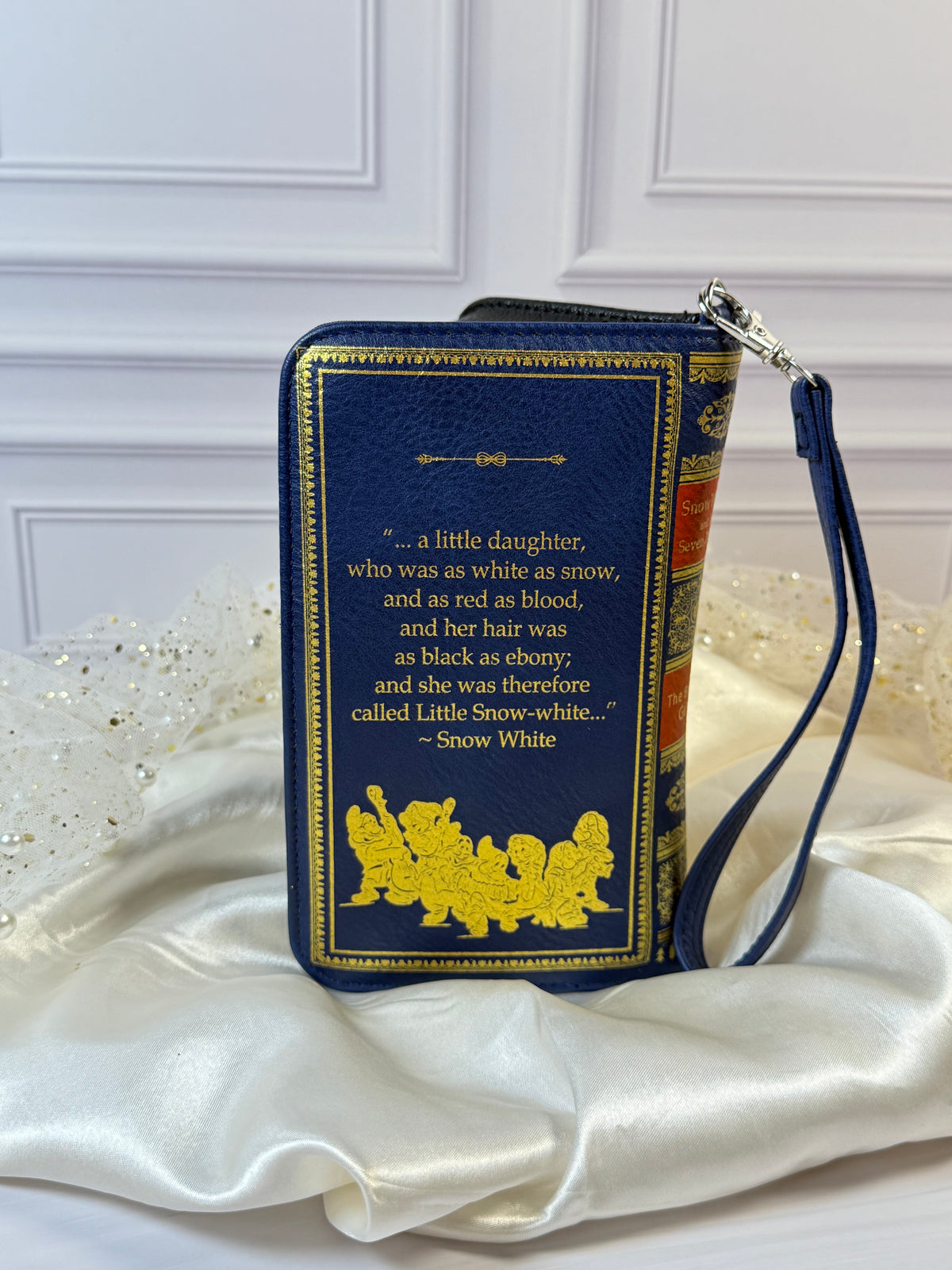 Back of Snow White book wallet showing gold quote and Seven Dwarfs artwork on navy vinyl.
