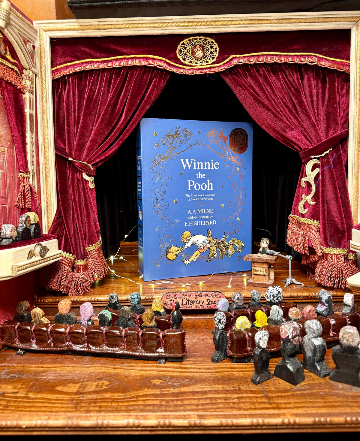 Winnie-the-Pooh: The Complete Collection hardcover gift book displayed in a miniature theatrical setting with red curtains, part of the StoryGiftStudio™ literary collection.