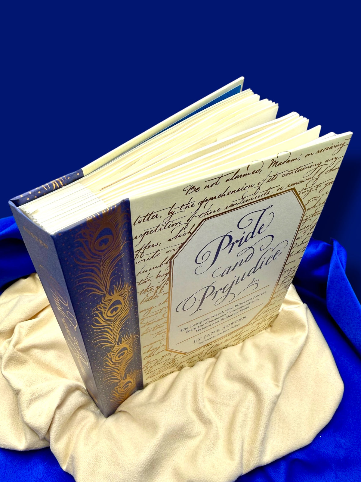 Angled view of the Pride and Prejudice deluxe edition hardcover standing on gold satin, showing its decorative blue and gold binding.
