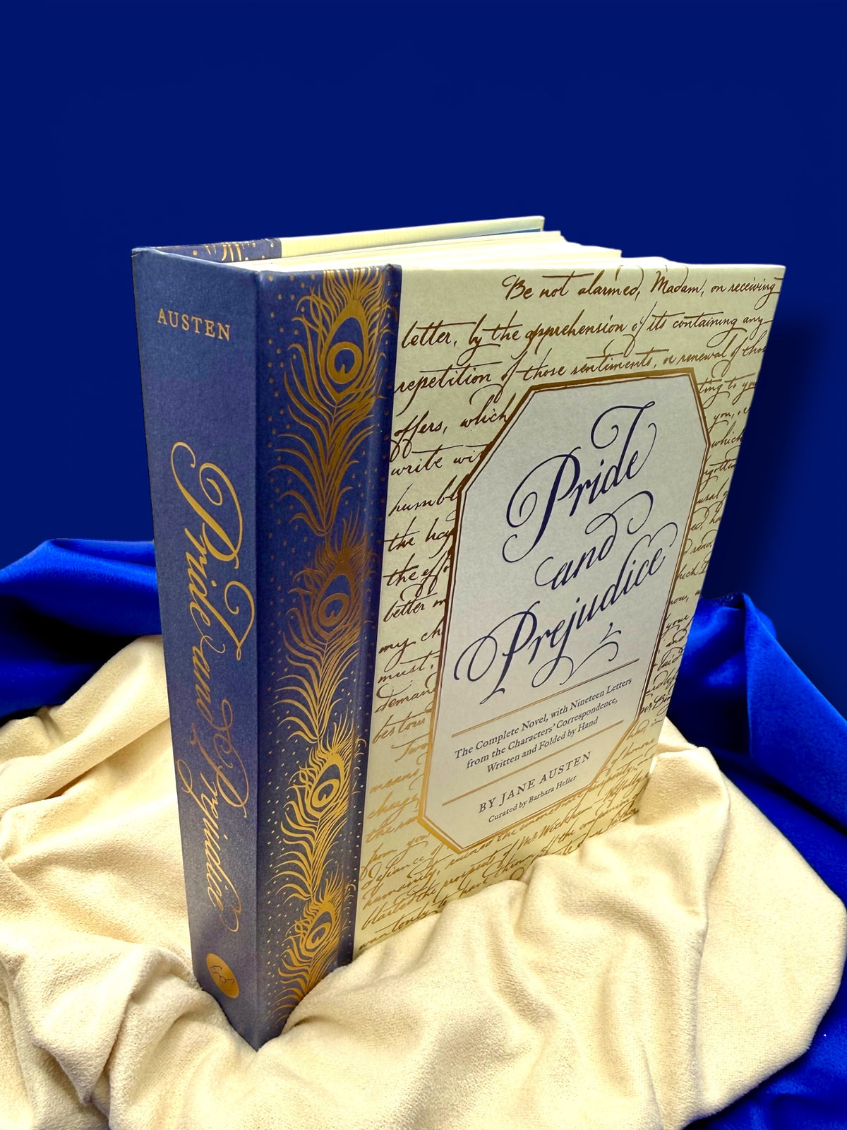 Angled view of the Pride and Prejudice deluxe edition hardcover standing on gold satin, showing its decorative blue and gold binding.