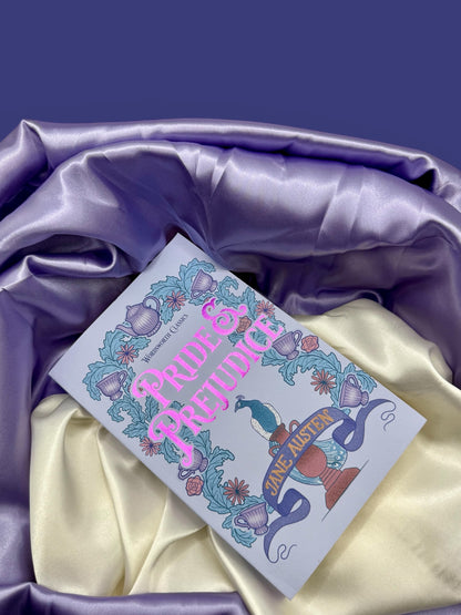 Pride and Prejudice by Jane Austen paperback photographed at an angle on dark purple fabric, highlighting its decorative illustrated cover.