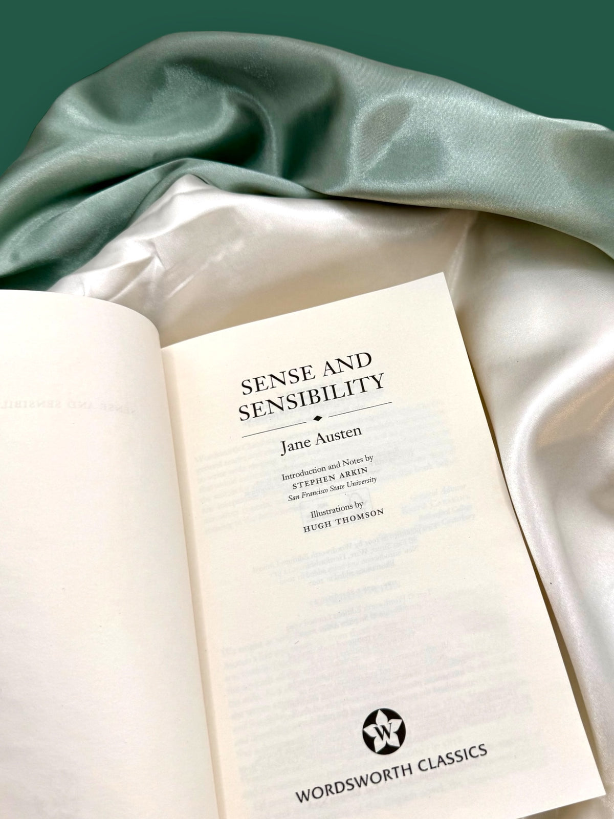 Open Sense and Sensibility Wordsworth Classics paperback showing its interior title page, photographed on soft ivory fabric.