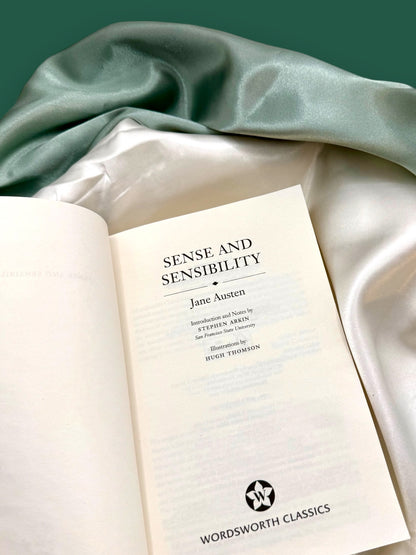 Open Sense and Sensibility Wordsworth Classics paperback showing its interior title page, photographed on soft ivory fabric.
