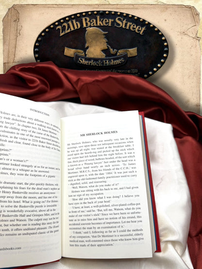 Open pages of The Hound of the Baskervilles showing the introduction and opening chapter Mr Sherlock Holmes, with black serif text printed on ivory paper.
