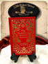 The Memoirs of Sherlock Holmes by Sir Arthur Conan Doyle, red clothbound hardcover with elaborate gold floral ornamentation, displayed on a wooden book stand beneath a 221B Baker Street sign.