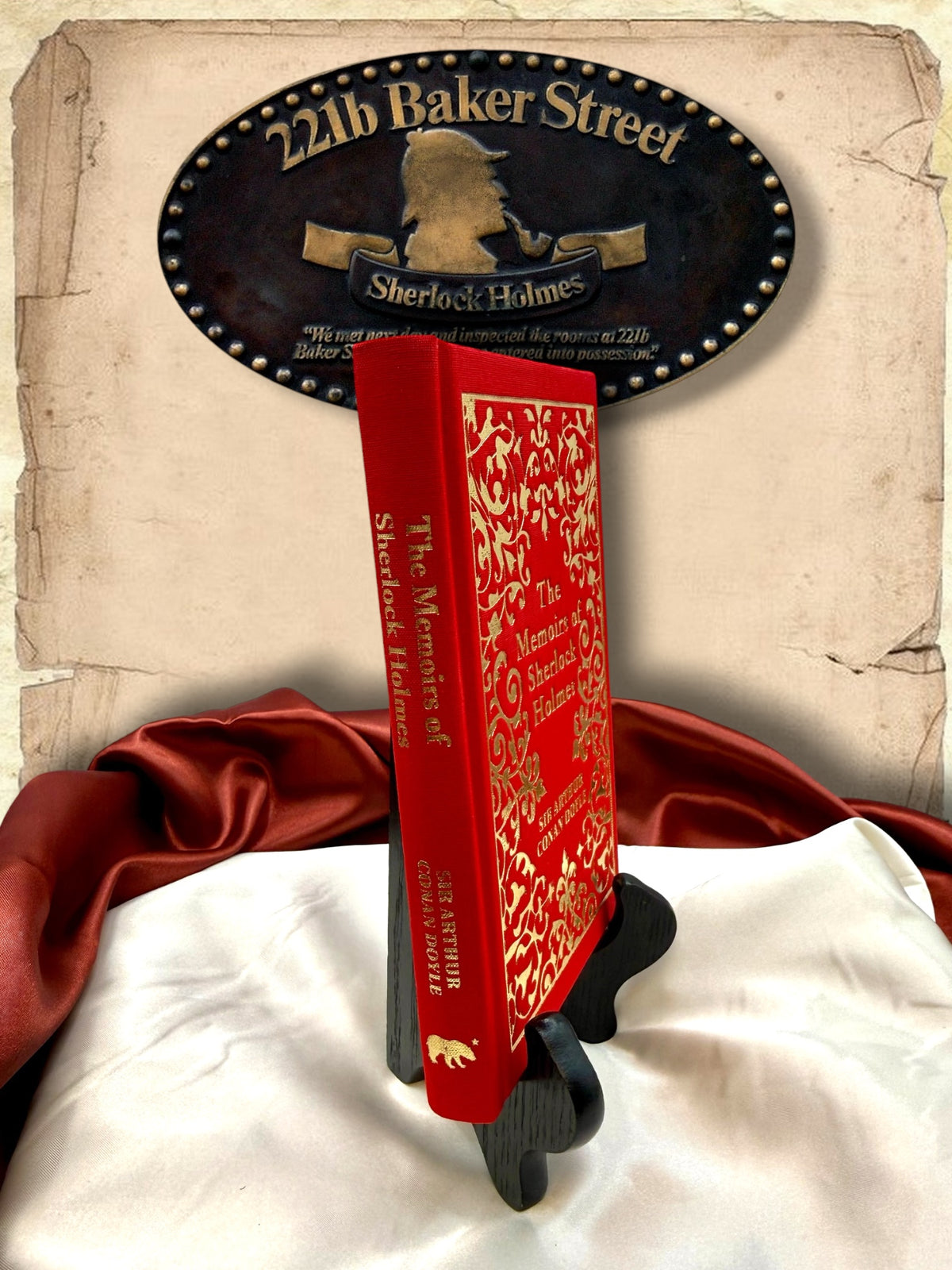 Angled spine view of The Memoirs of Sherlock Holmes red clothbound hardcover, showing gold spine lettering, decorative front cover, and author name.