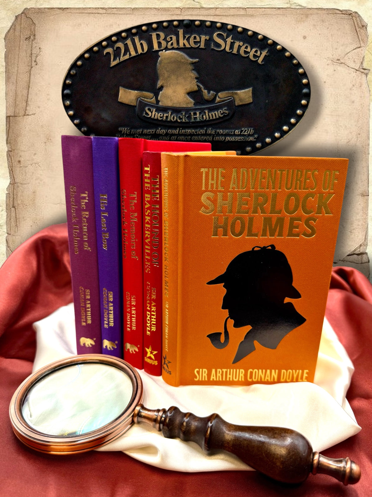 The Return of Sherlock Holmes purple clothbound hardcover displayed alongside other colorful Sherlock Holmes books, a magnifying glass, and detective-themed studio decorations.