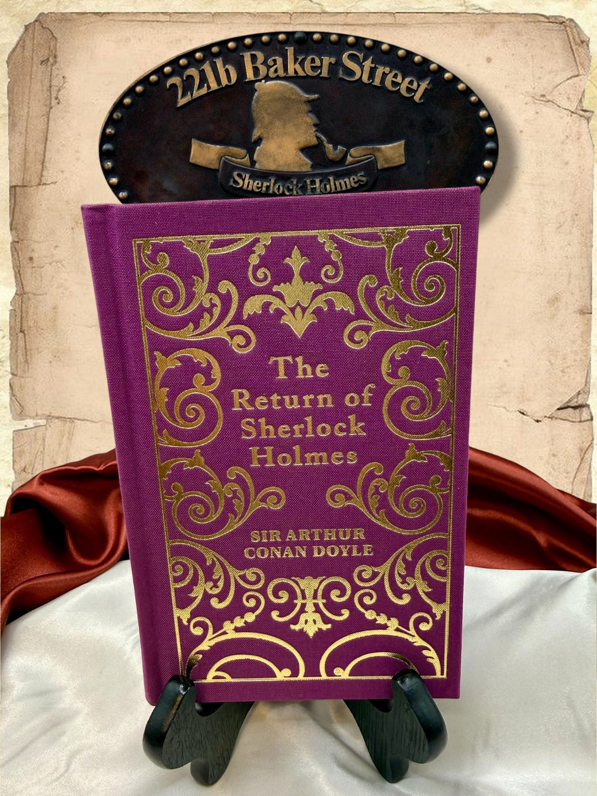 The Return of Sherlock Holmes by Sir Arthur Conan Doyle, purple clothbound hardcover with ornate gold cover decoration, displayed on a wooden stand in the StoryGiftStudio studio.