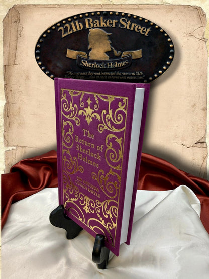 Three-quarter view of The Return of Sherlock Holmes purple clothbound book showing its gold-decorated front cover, hardcover binding, and white page edges.