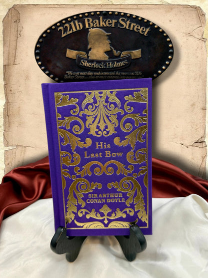 His Last Bow by Sir Arthur Conan Doyle, purple clothbound Sherlock Holmes hardcover with elaborate gold floral decoration, displayed beneath a 221B Baker Street sign.