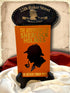 Orange hardcover The Adventures of Sherlock Holmes by Arthur Conan Doyle displayed beside a red Sherlock Holmes book wallet, with a 221B Baker Street plaque and satin fabric.