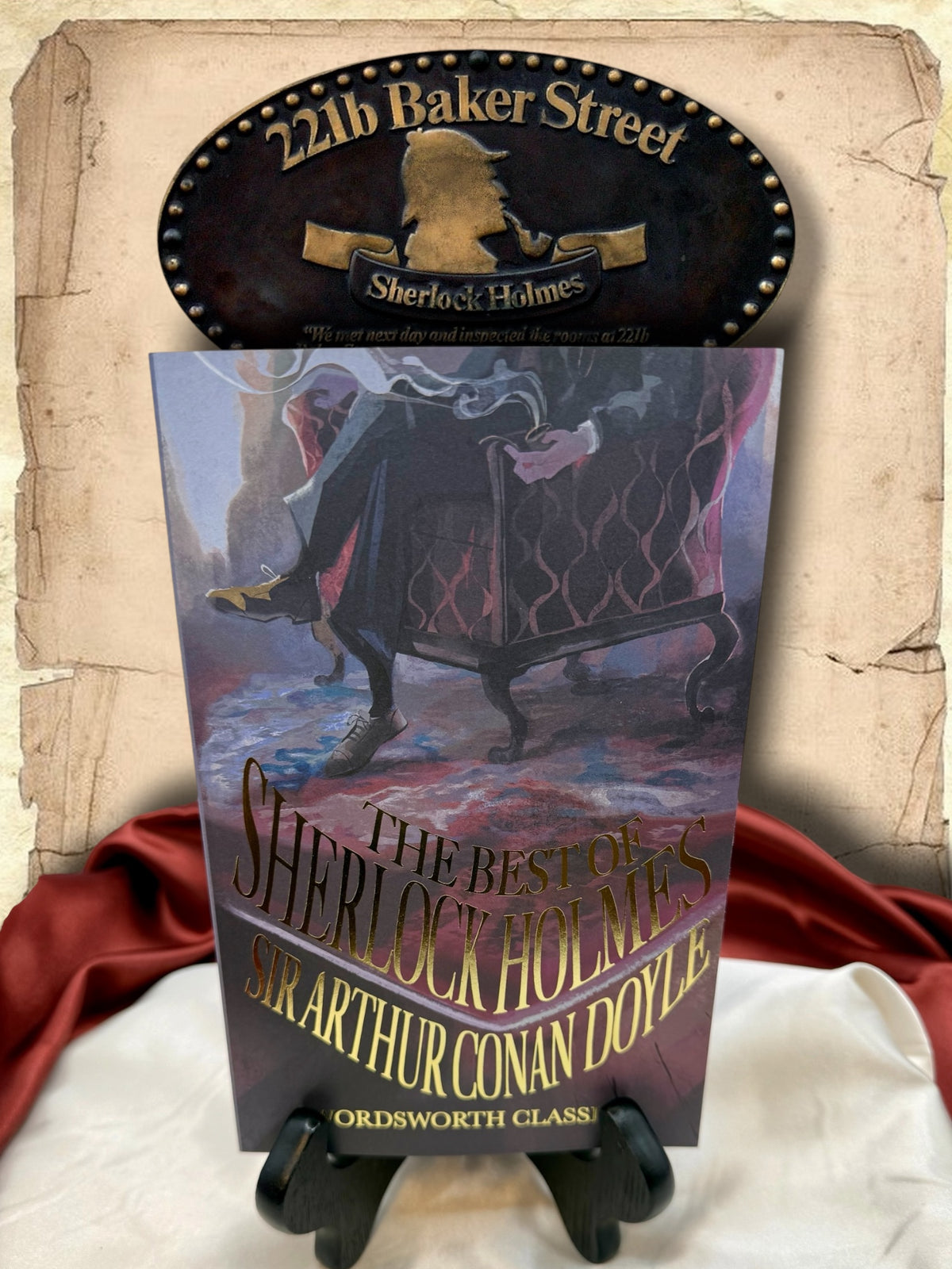 The Best of Sherlock Holmes by Sir Arthur Conan Doyle, Wordsworth Classics paperback with illustrated purple and blue cover and gold lettering, displayed beneath a 221B Baker Street sign.