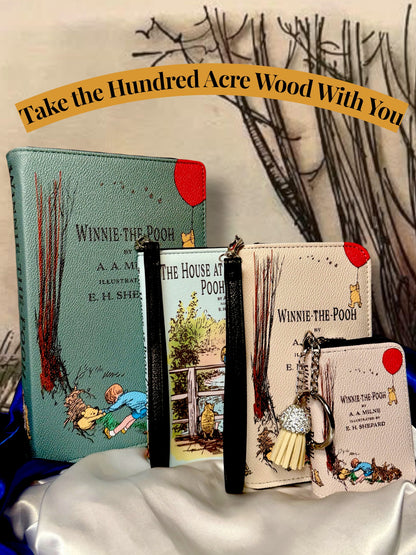 Coordinating Winnie-the-Pooh literary accessories displayed together, including illustrated book wallets, The House at Pooh Corner accessory, and miniature book bag charm.