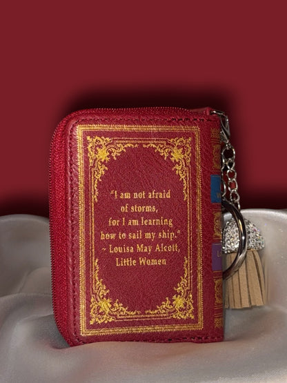 Back of Little Women book bag charm featuring a Louisa May Alcott quotation in gold lettering, ornate gold border, and attached silver keyring with tassel.