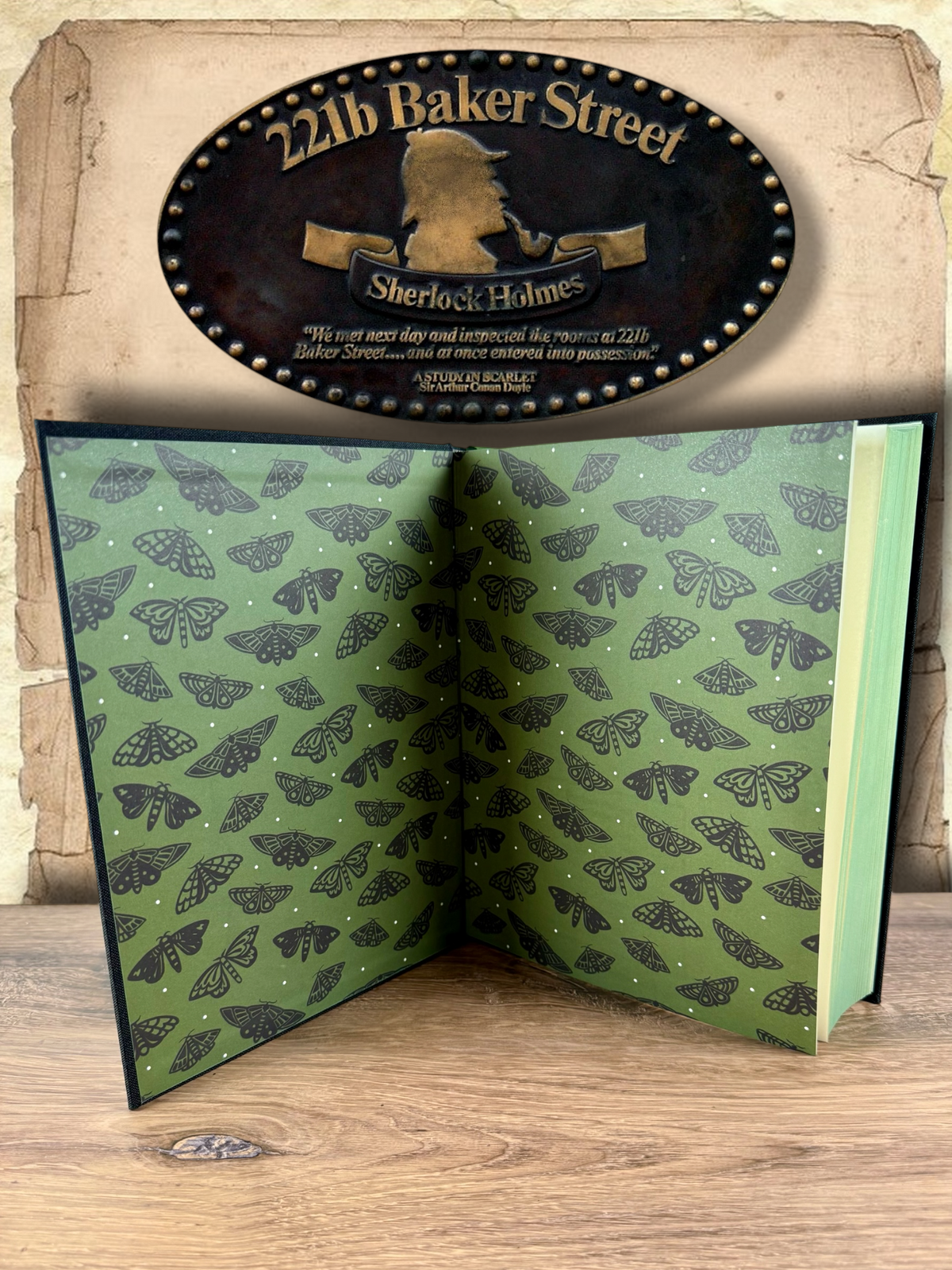 The Complete Stories of Sherlock Holmes hardcover opened to reveal decorative green endpapers patterned with black moth illustrations and small white dots.