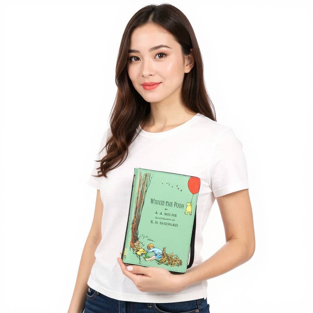 Model carrying The House at Pooh Corner Winnie-the-Pooh book clutch purse, demonstrating its size and everyday crossbody handbag styling.