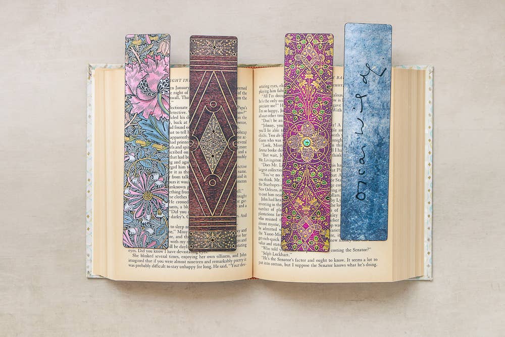 Open book with four colorful bookmarks on a neutral background
