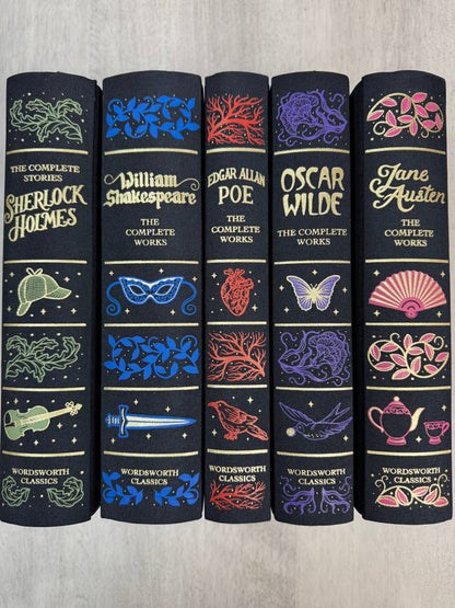 Set of five classic literature books with decorative covers on a wooden surface.