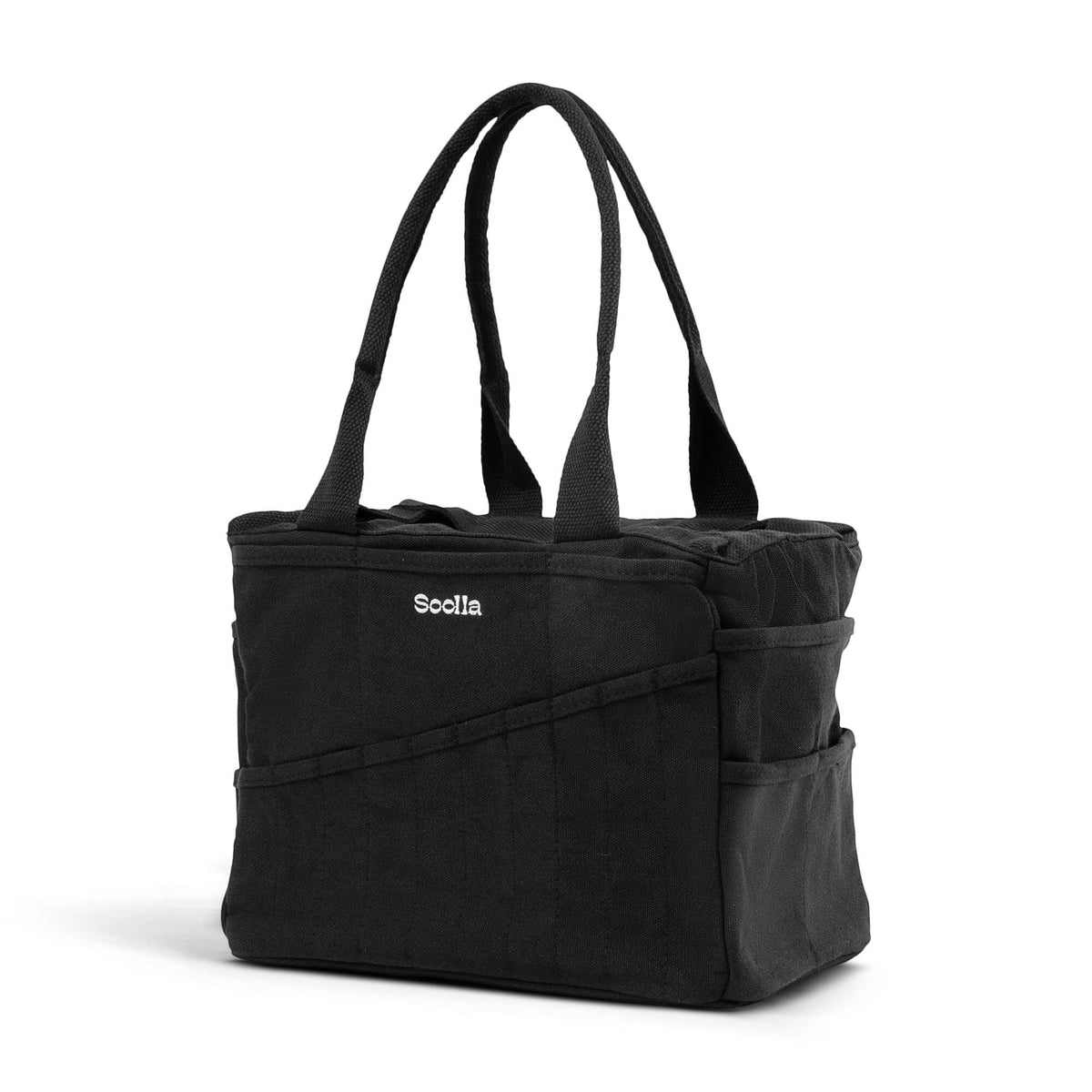 A black canvas Soolla Studio Artist tote bag with dual shoulder straps and a white ogo on the front, shown on a clean white background.
