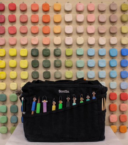 Blackout Soolla Studio Artist Bag with colorful hooks on a wooden pegboard background