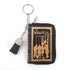 The Wizard of Oz miniature book-shaped vinyl coin purse and bag charm featuring colorful storybook cover artwork, a zippered compartment, and keychain attachment.
